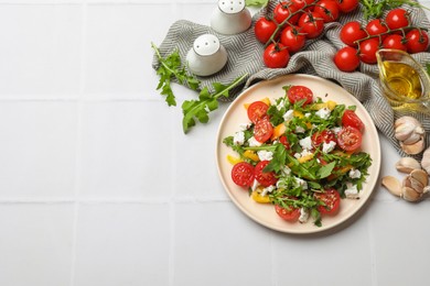 Photo of Tasty salad with arugula, cheese and vegetables on white tiled table, flat lay. Space for text