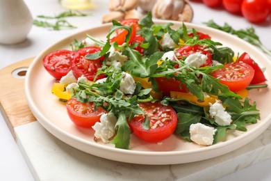 Photo of Tasty salad with arugula, cheese and vegetables on white table, closeup