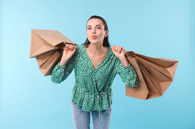 Beautiful woman with shopping bags on light blue background