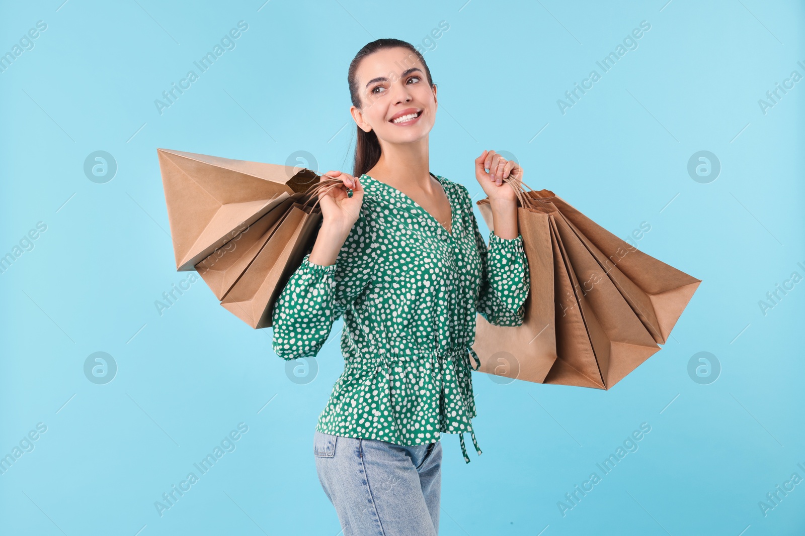 Photo of Smiling woman with shopping bags on light blue background