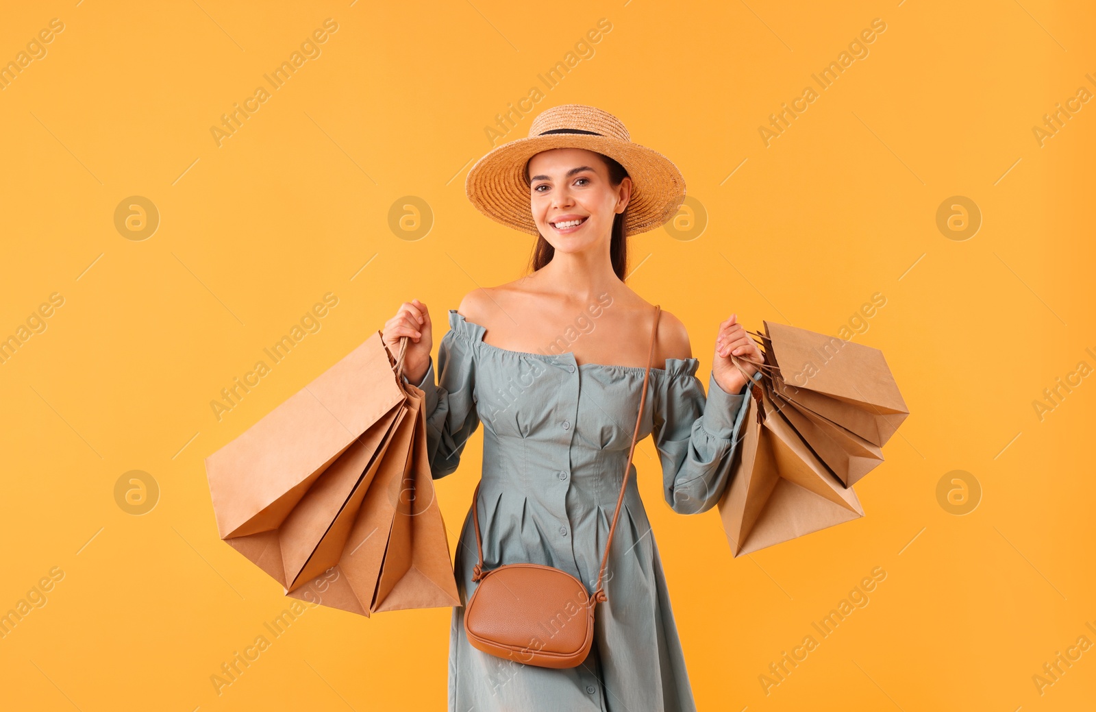 Photo of Smiling woman with shopping bags on yellow background