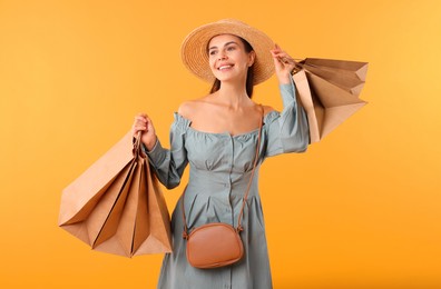 Smiling woman with shopping bags on yellow background