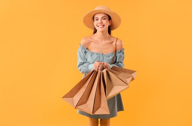 Smiling woman with shopping bags on yellow background