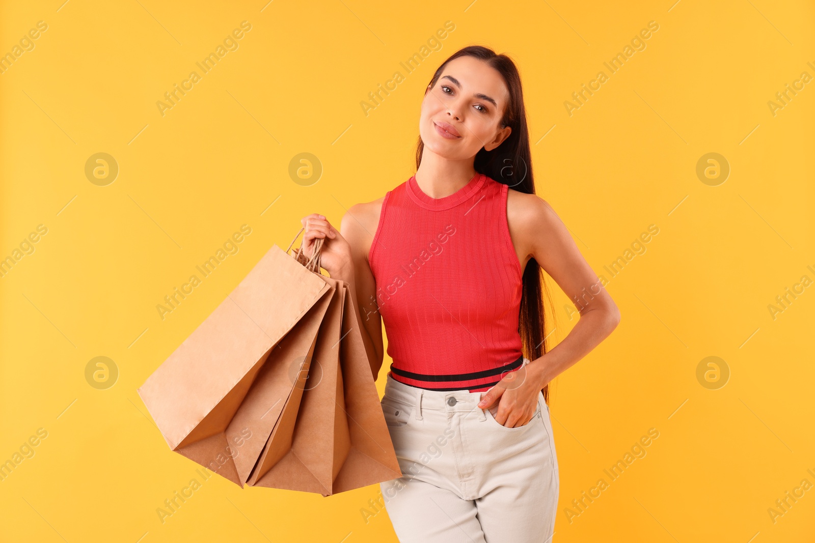 Photo of Beautiful woman with shopping bags on yellow background