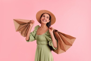 Smiling woman with shopping bags on pink background