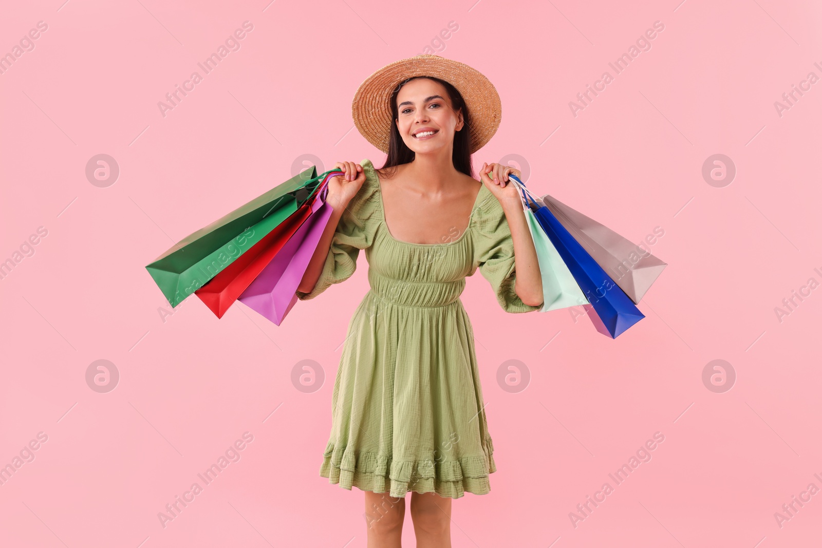 Photo of Smiling woman with colorful shopping bags on pink background