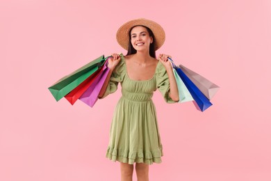 Photo of Smiling woman with colorful shopping bags on pink background