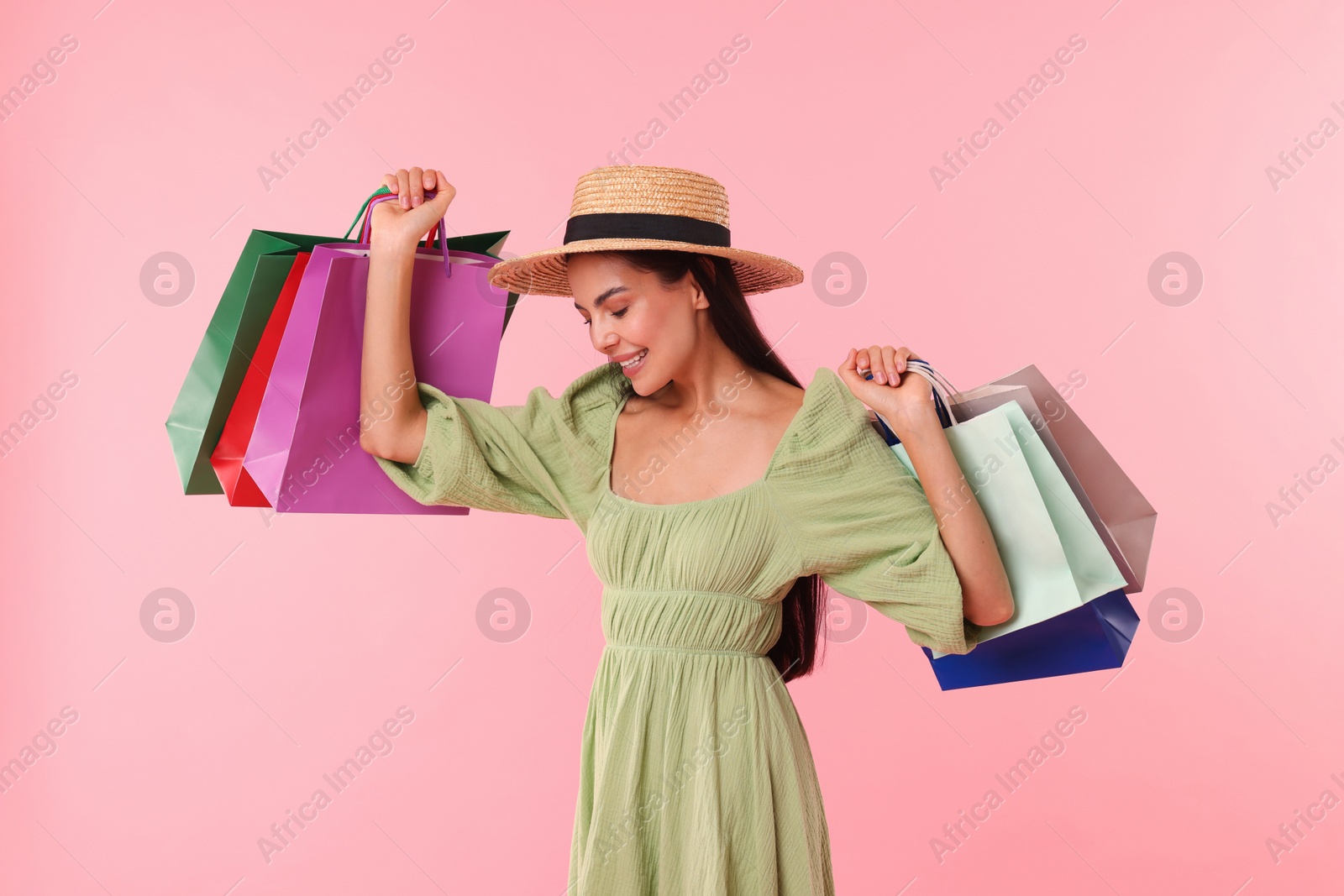 Photo of Smiling woman with colorful shopping bags on pink background