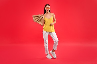 Photo of Smiling woman with shopping bags on red background