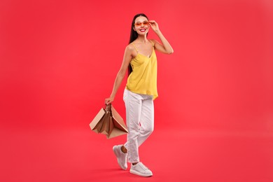 Smiling woman with shopping bags on red background