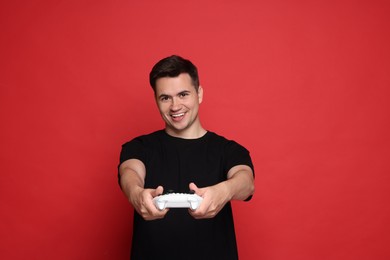 Photo of Happy young man playing video games with controller on red background