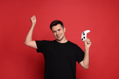 Photo of Happy young man with controller on red background