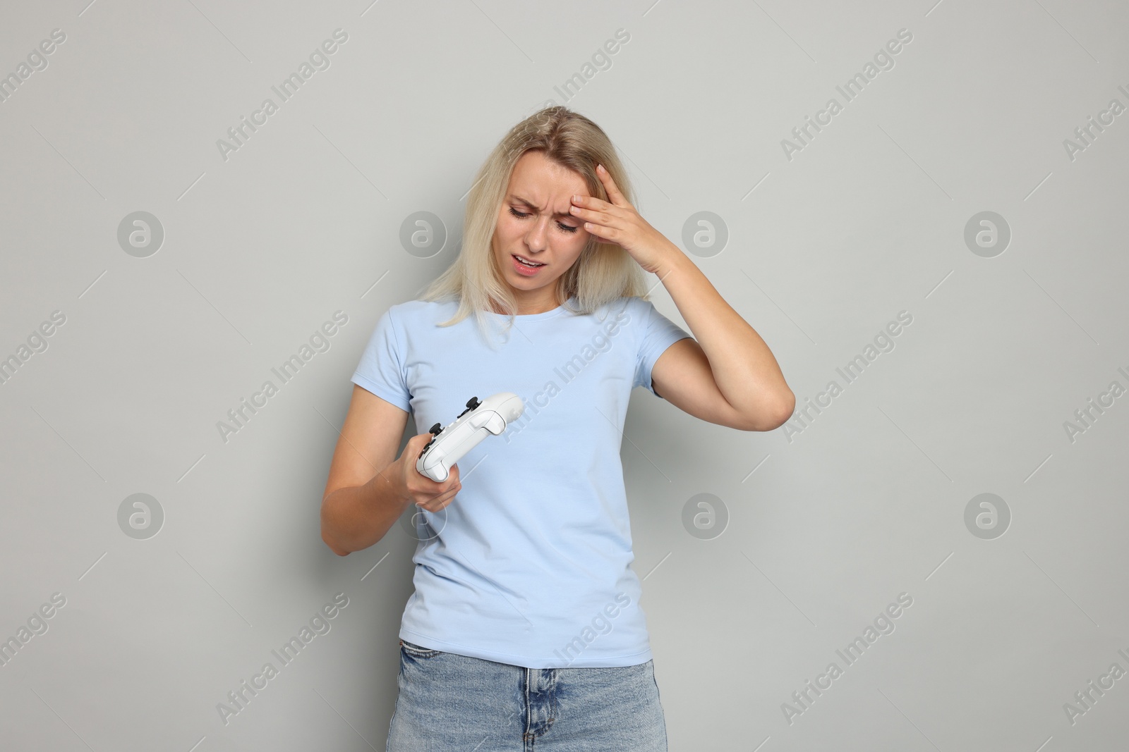 Photo of Unhappy woman with controller on gray background