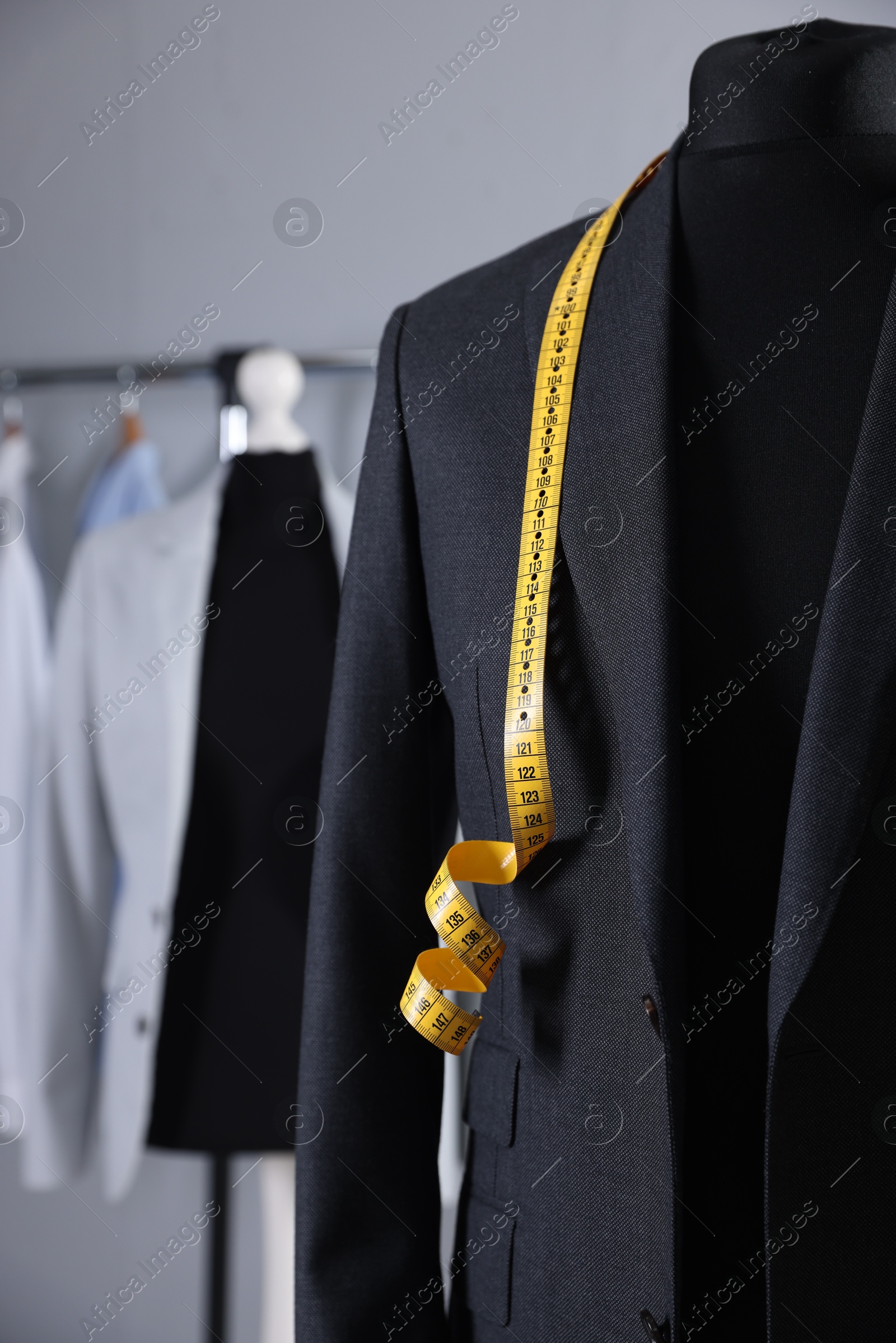 Photo of Male mannequin with jacket and measuring tape in tailor shop, closeup