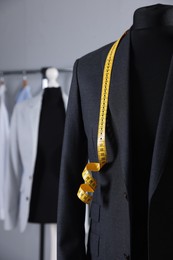 Male mannequin with jacket and measuring tape in tailor shop, closeup