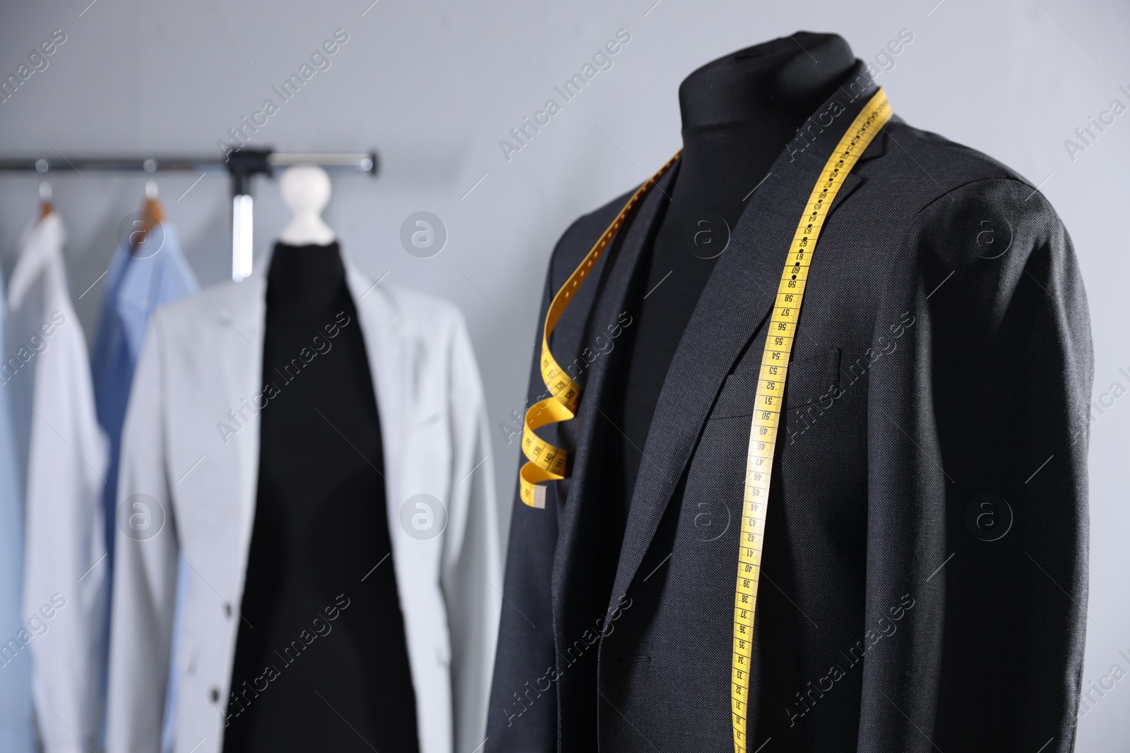 Photo of Male mannequin with jacket and measuring tape in tailor shop, closeup