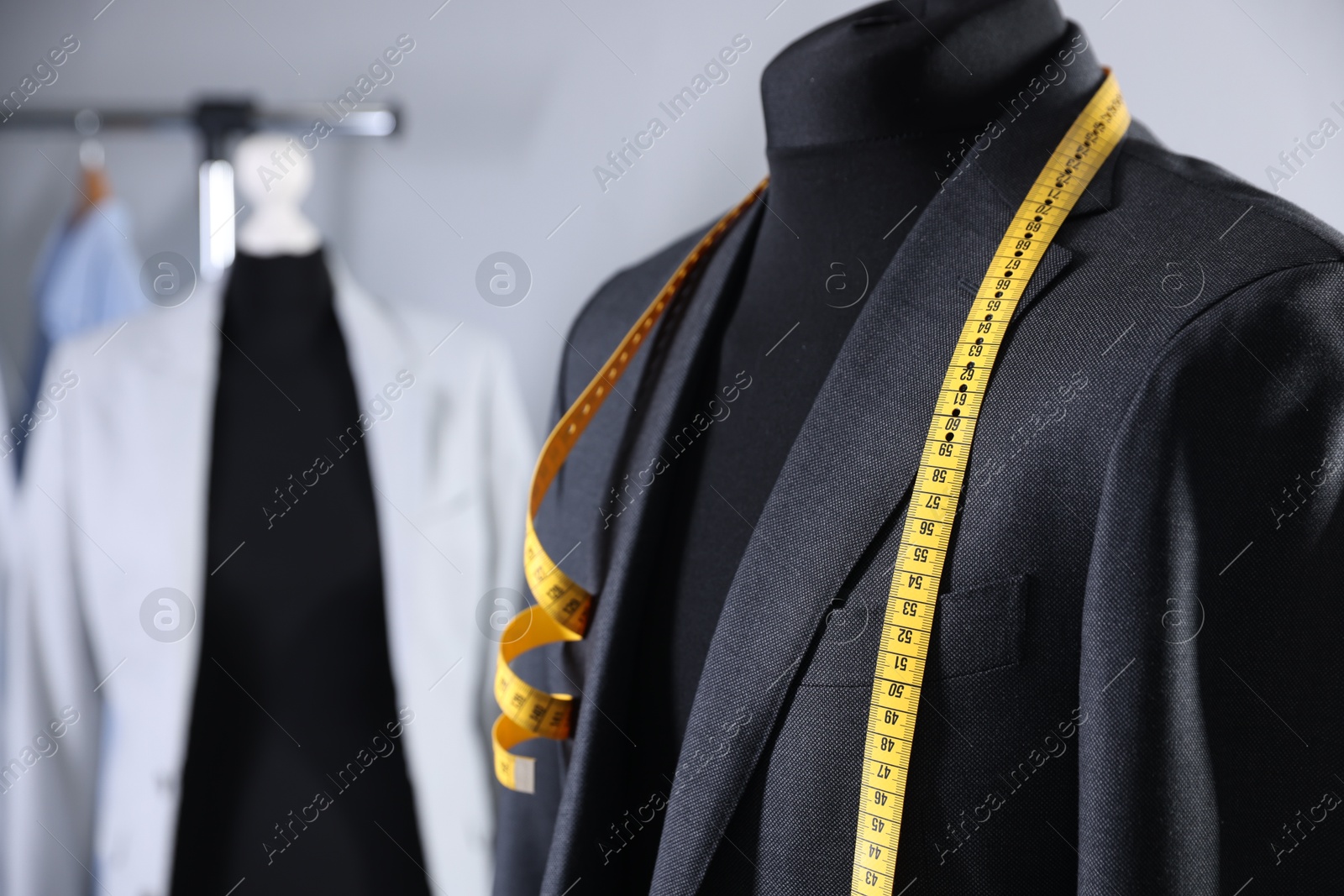 Photo of Male mannequin with jacket and measuring tape in tailor shop, closeup