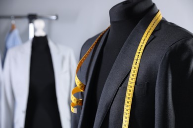 Photo of Male mannequin with jacket and measuring tape in tailor shop, closeup