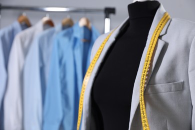 Female mannequin with jacket and measuring tape in tailor shop, closeup