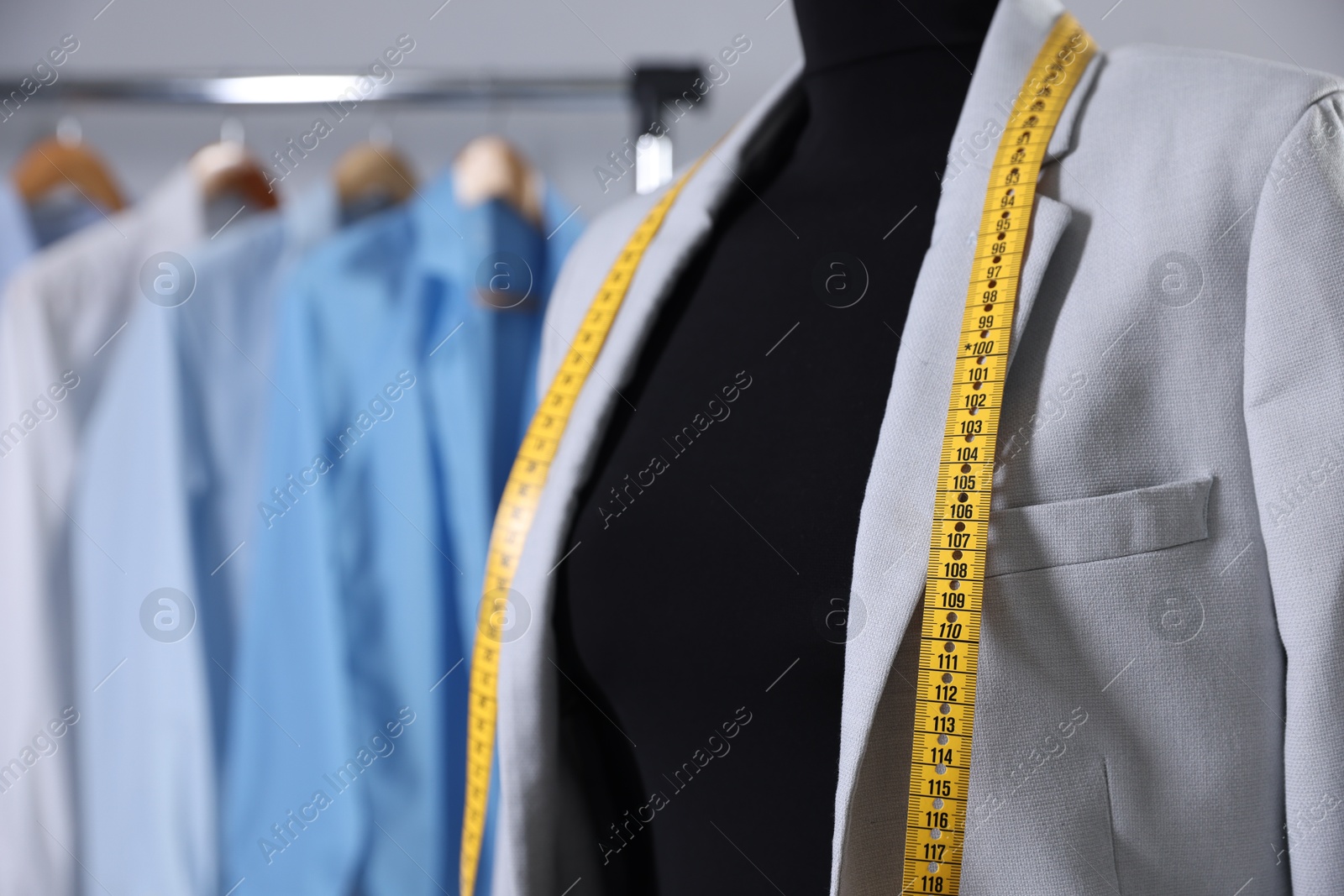 Photo of Female mannequin with jacket and measuring tape in tailor shop, closeup