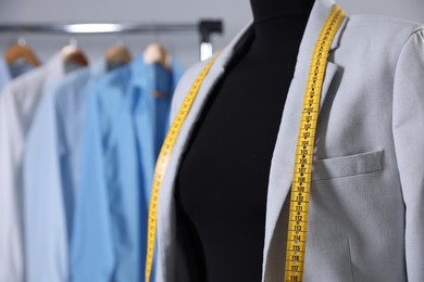 Photo of Female mannequin with jacket and measuring tape in tailor shop, closeup