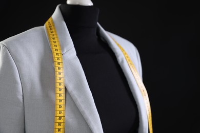 Photo of Female mannequin with gray jacket and measuring tape on black background, closeup