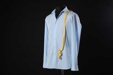 Male mannequin with shirt and measuring tape on black background