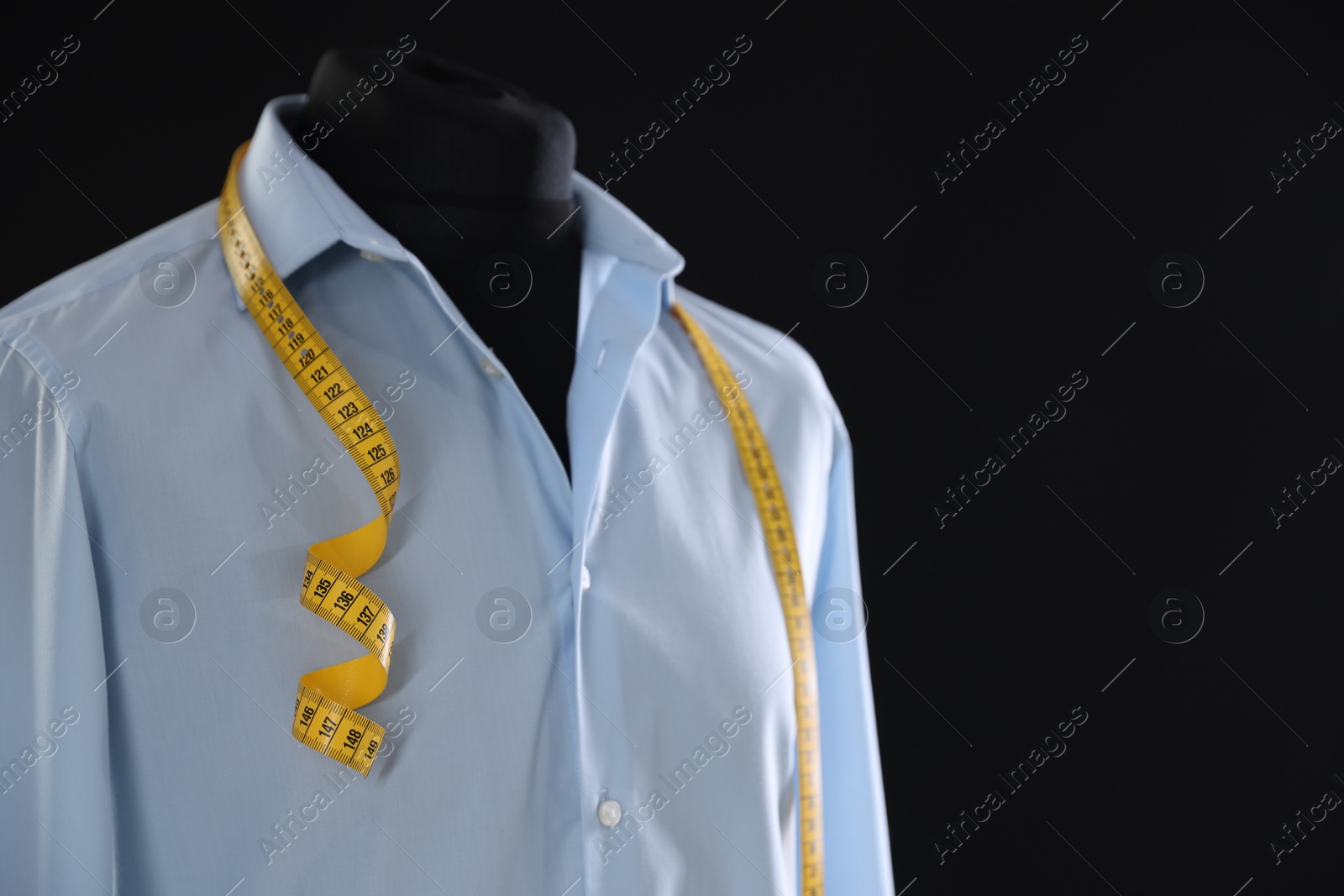 Photo of Male mannequin with shirt and measuring tape on black background, closeup. Space for text