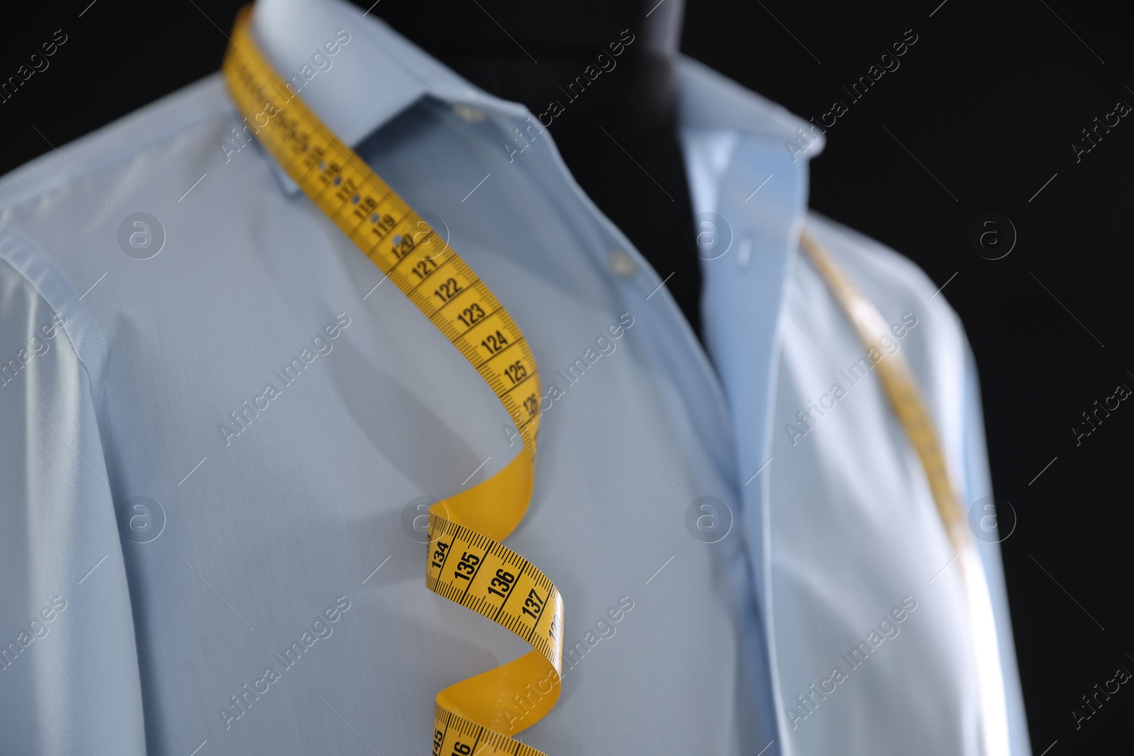 Photo of Male mannequin with shirt and measuring tape on black background, closeup