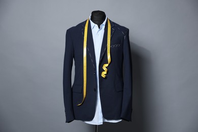 Semi-ready jacket, shirt and measuring tape on mannequin against gray background