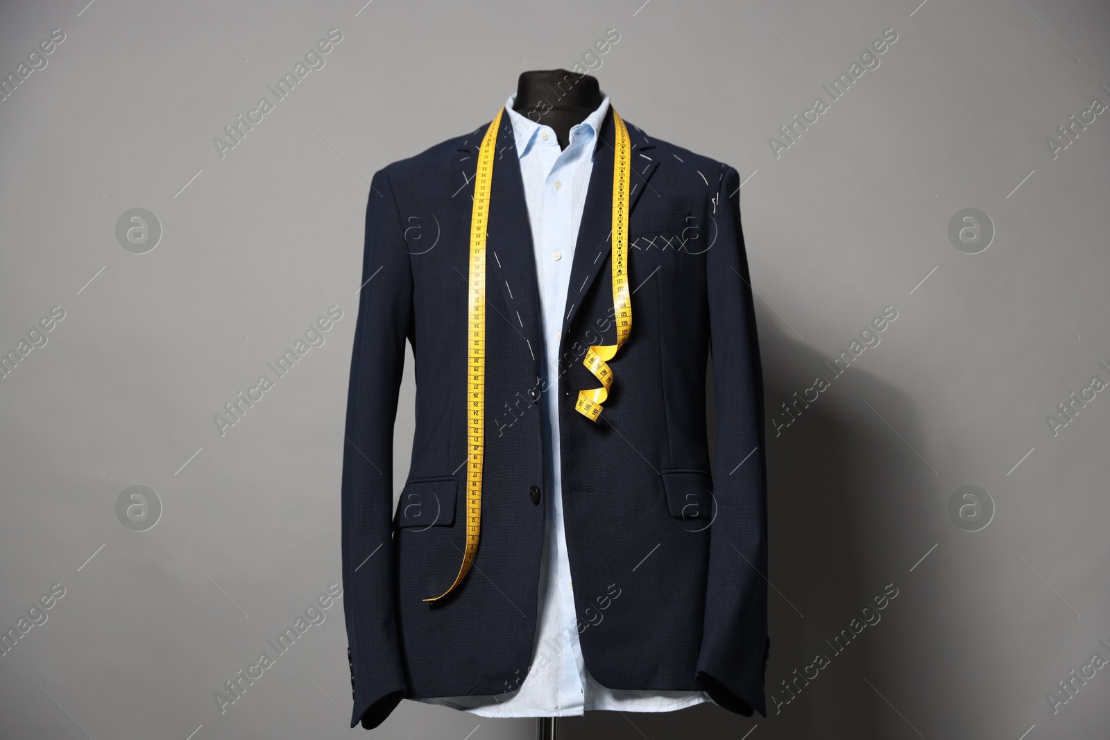 Photo of Semi-ready jacket, shirt and measuring tape on mannequin against gray background