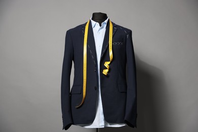 Semi-ready jacket, shirt and measuring tape on mannequin against gray background