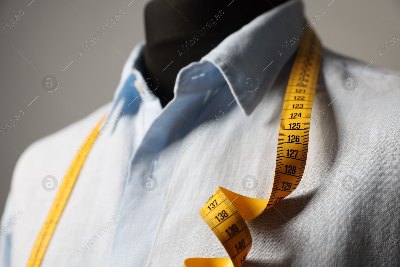 Photo of Male mannequin with shirt and measuring tape on gray background, closeup