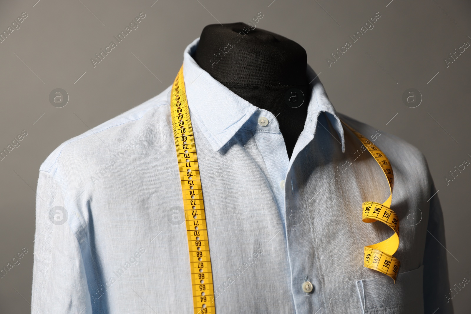 Photo of Male mannequin with shirt and measuring tape on gray background, closeup