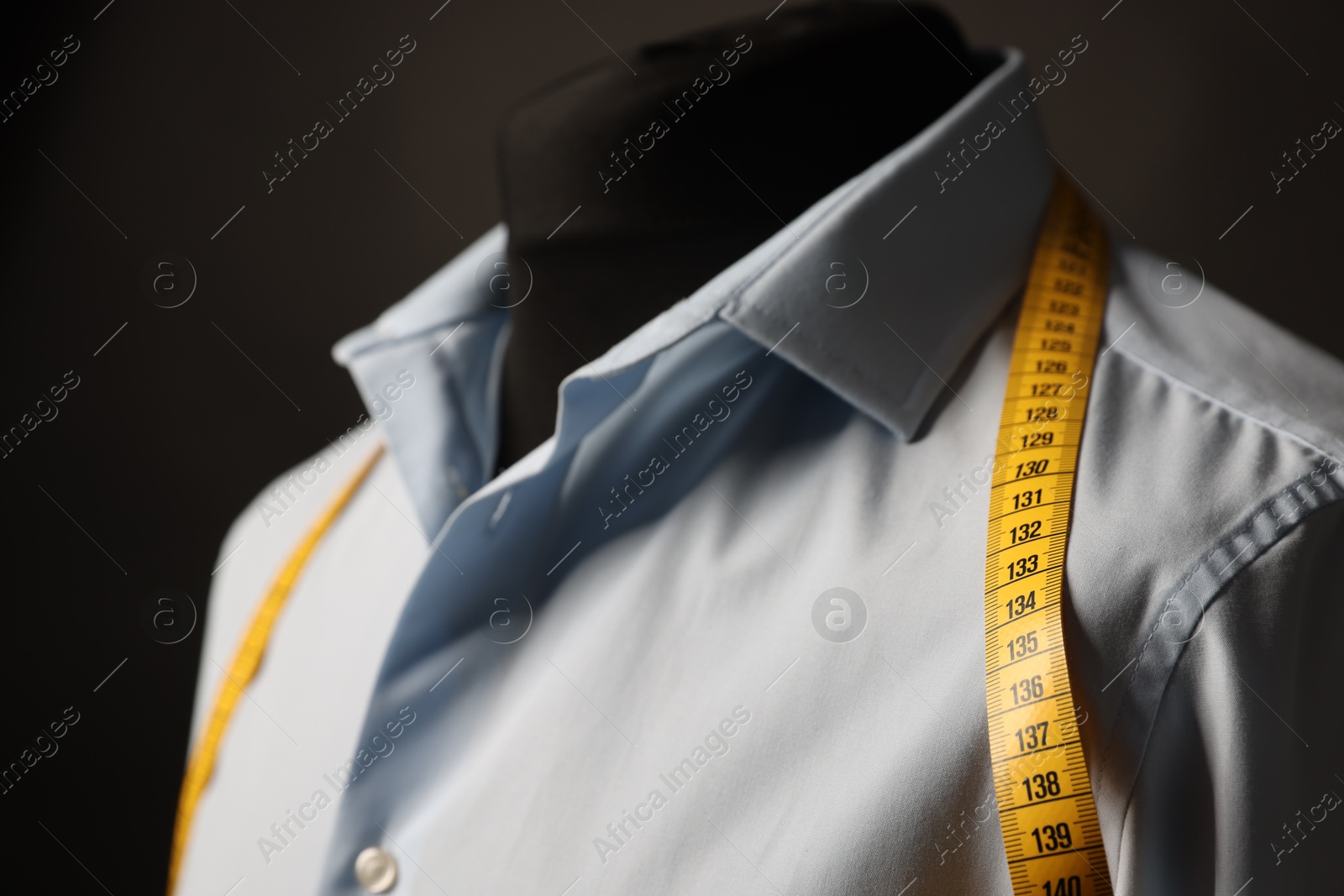 Photo of Male mannequin with shirt and measuring tape on dark background, closeup