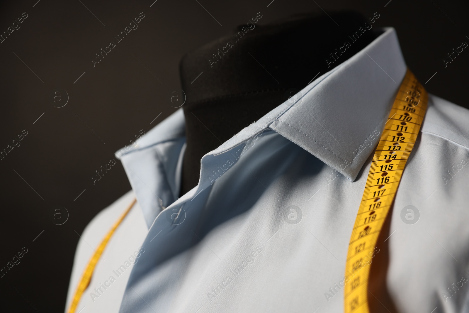 Photo of Male mannequin with shirt and measuring tape on dark background, closeup