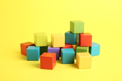 Photo of Many wooden colorful cubes on yellow background