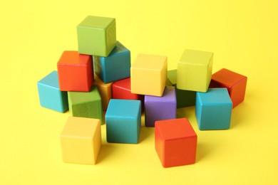 Photo of Many wooden colorful cubes on yellow background