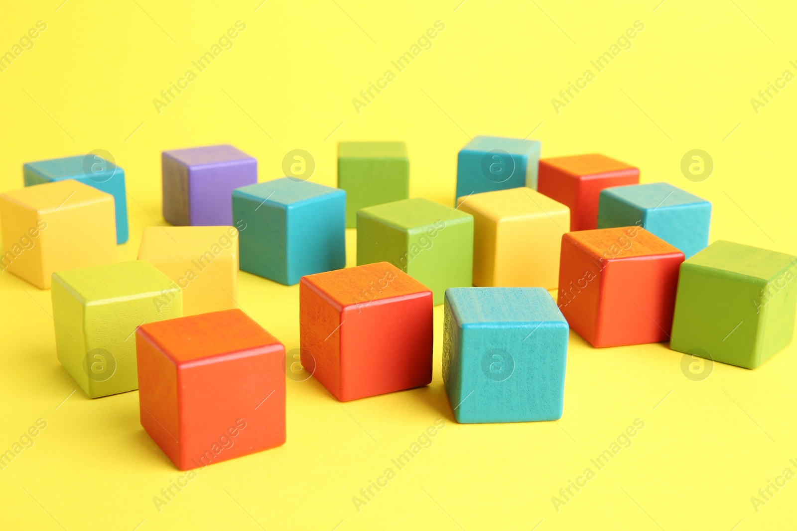 Photo of Many wooden colorful cubes on yellow background