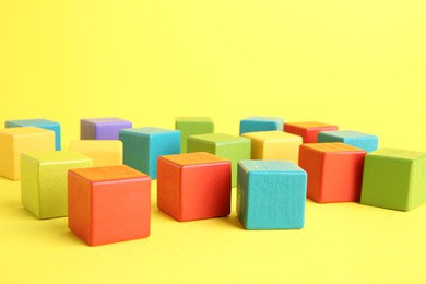 Photo of Many wooden colorful cubes on yellow background