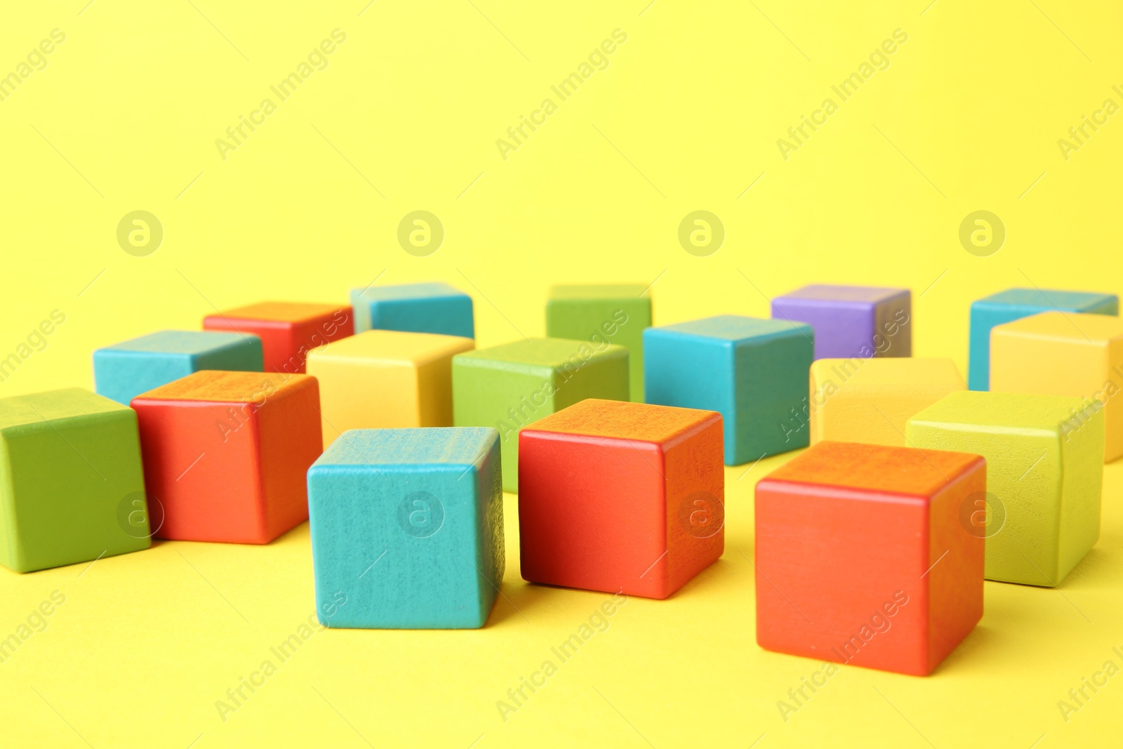 Photo of Many wooden colorful cubes on yellow background