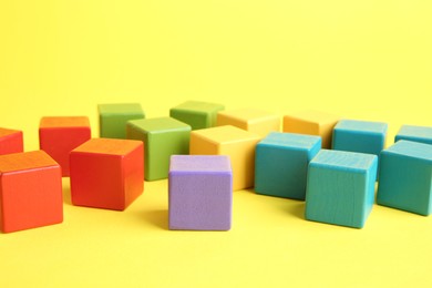 Photo of Many wooden colorful cubes on yellow background