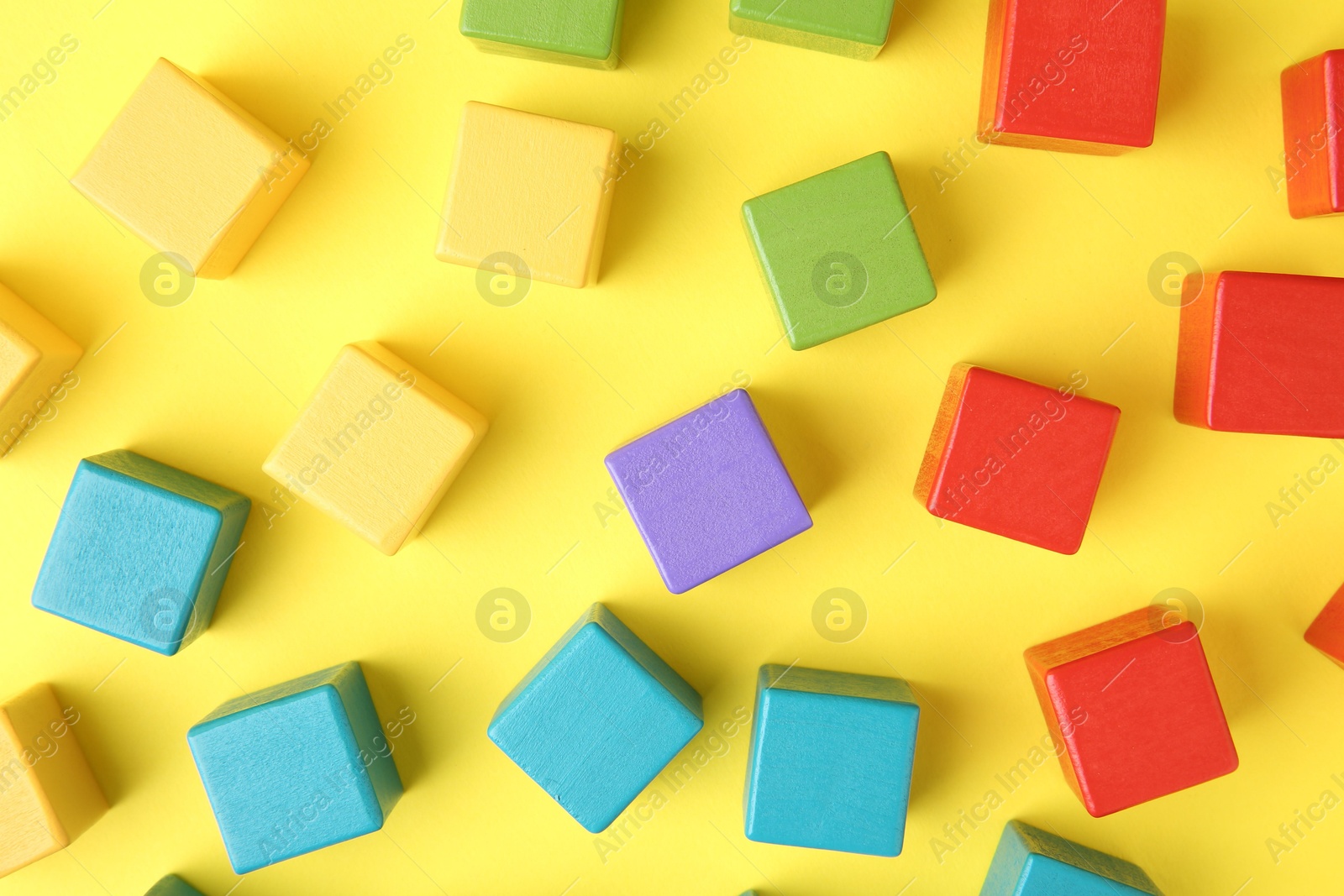 Photo of Many wooden colorful cubes on yellow background, flat lay