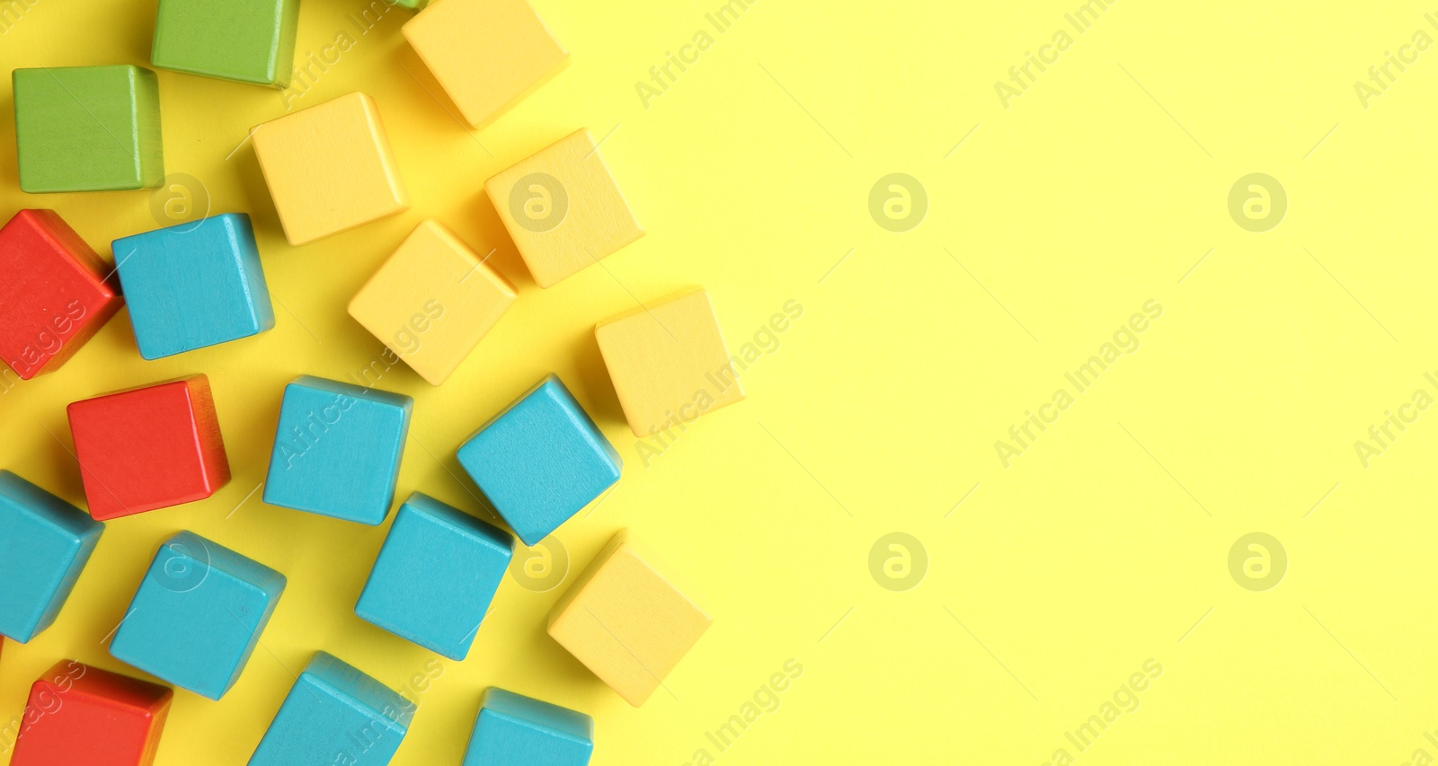 Photo of Many wooden colorful cubes on yellow background, flat lay. Space for text