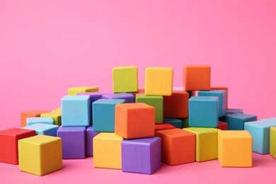 Photo of Many wooden colorful cubes on pink background