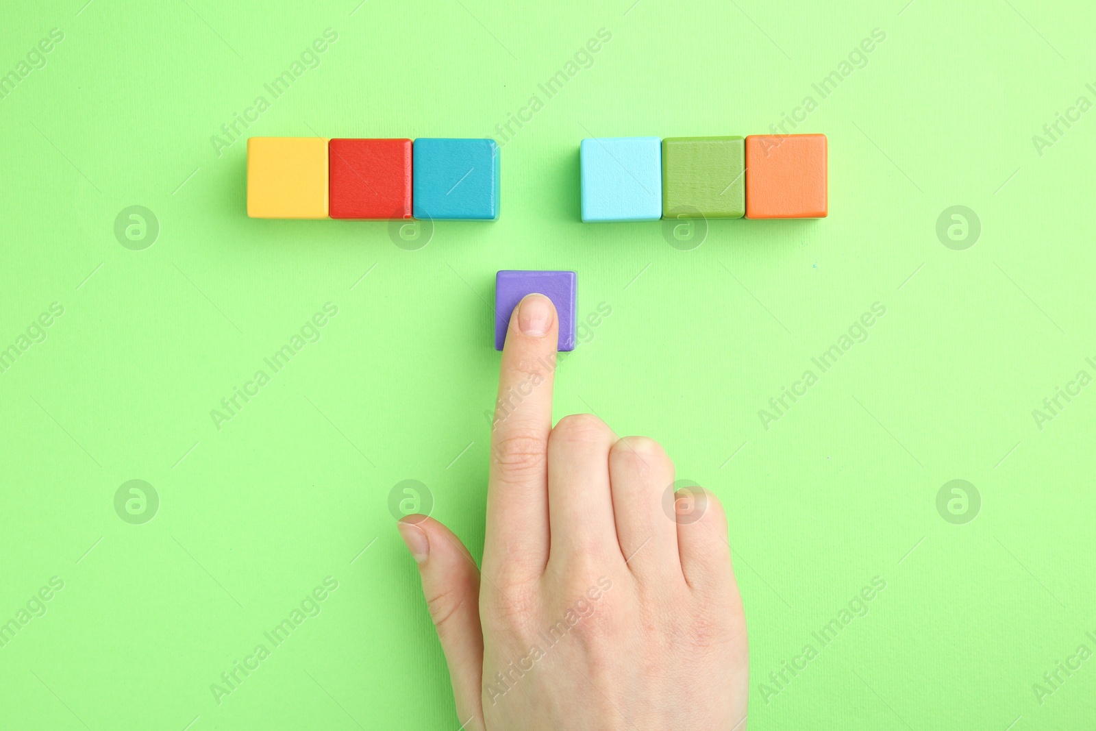 Photo of Woman with colorful cubes on green background, top view