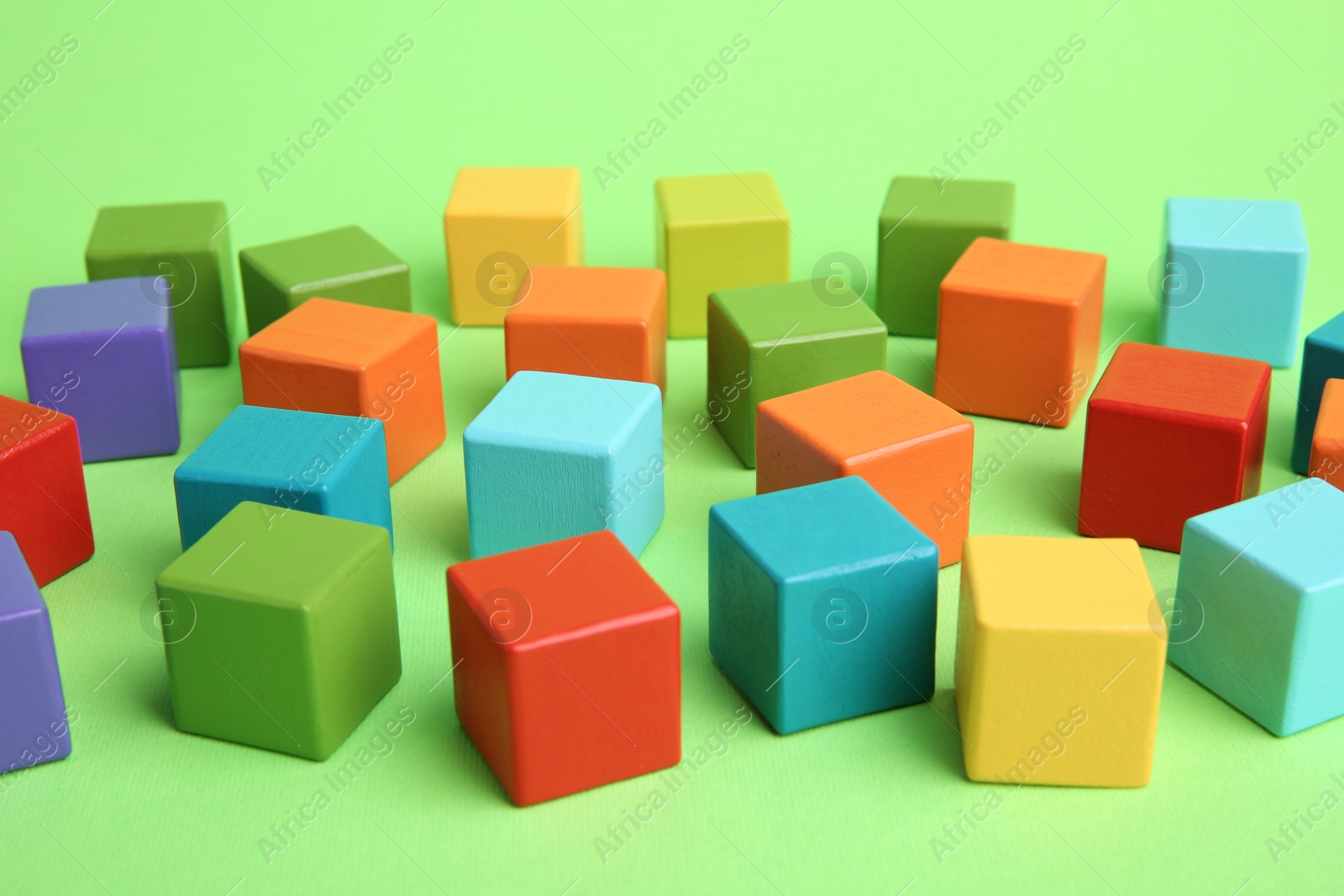 Photo of Many wooden colorful cubes on green background, closeup