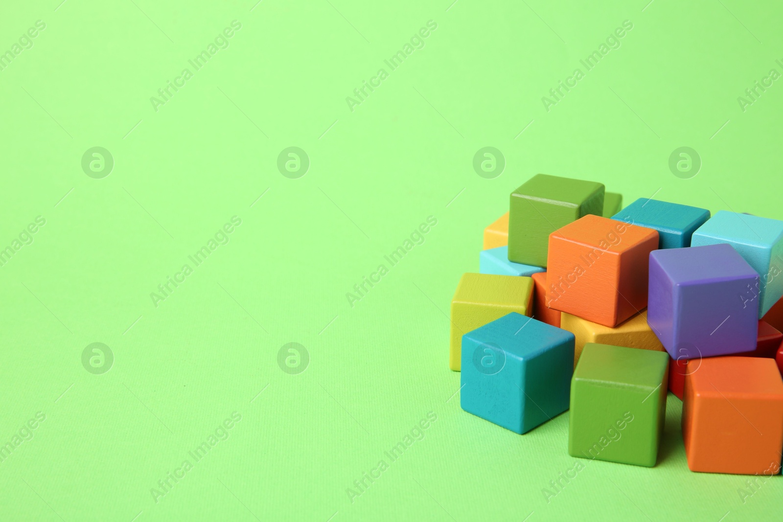 Photo of Many wooden colorful cubes on green background, space for text