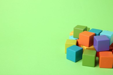 Photo of Many wooden colorful cubes on green background, space for text