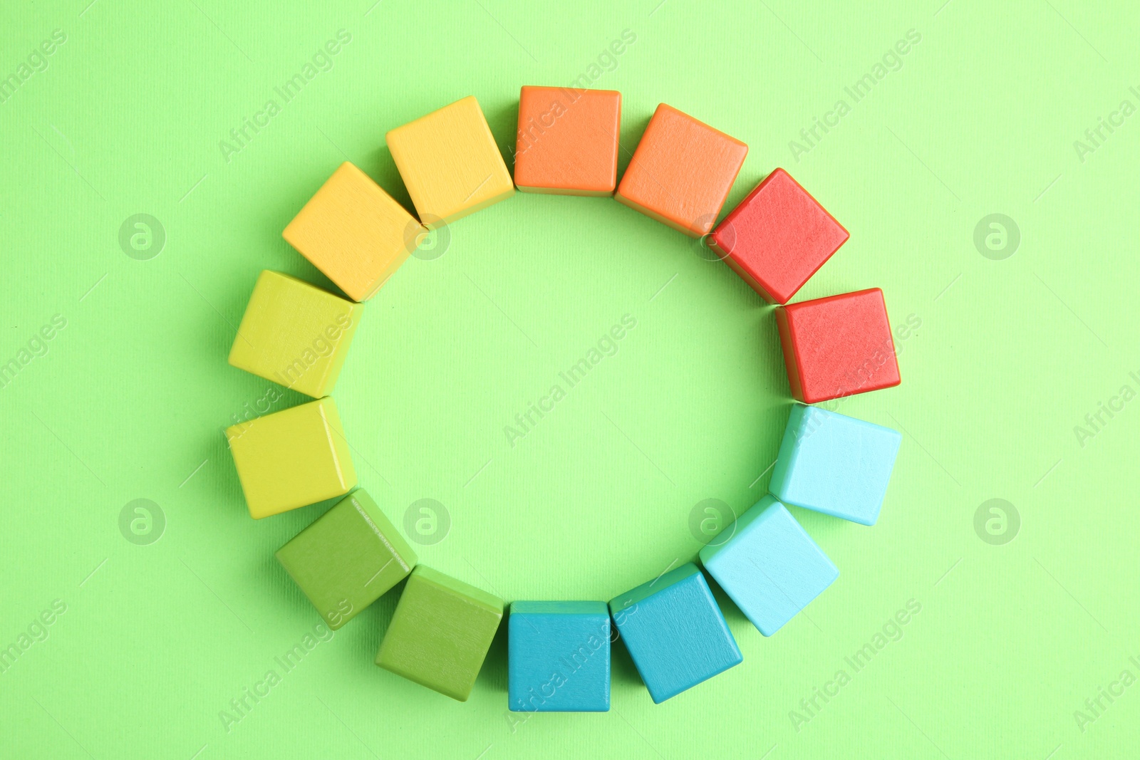 Photo of Many wooden colorful cubes on green background, top view. Space for text